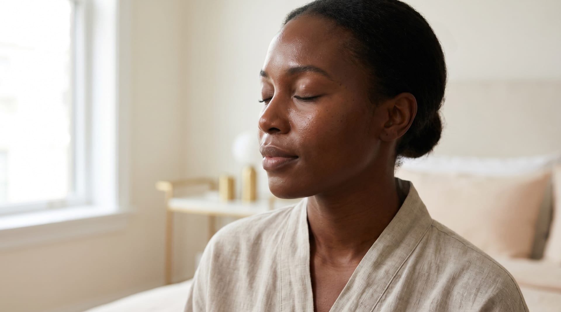 A woman with deeper skin tone, Fitzpatrick V to VI, with calm, healthy, even-toned and well-hydrated skin in a cream-toned treatment room at Melatone Skin Clinic Battersea