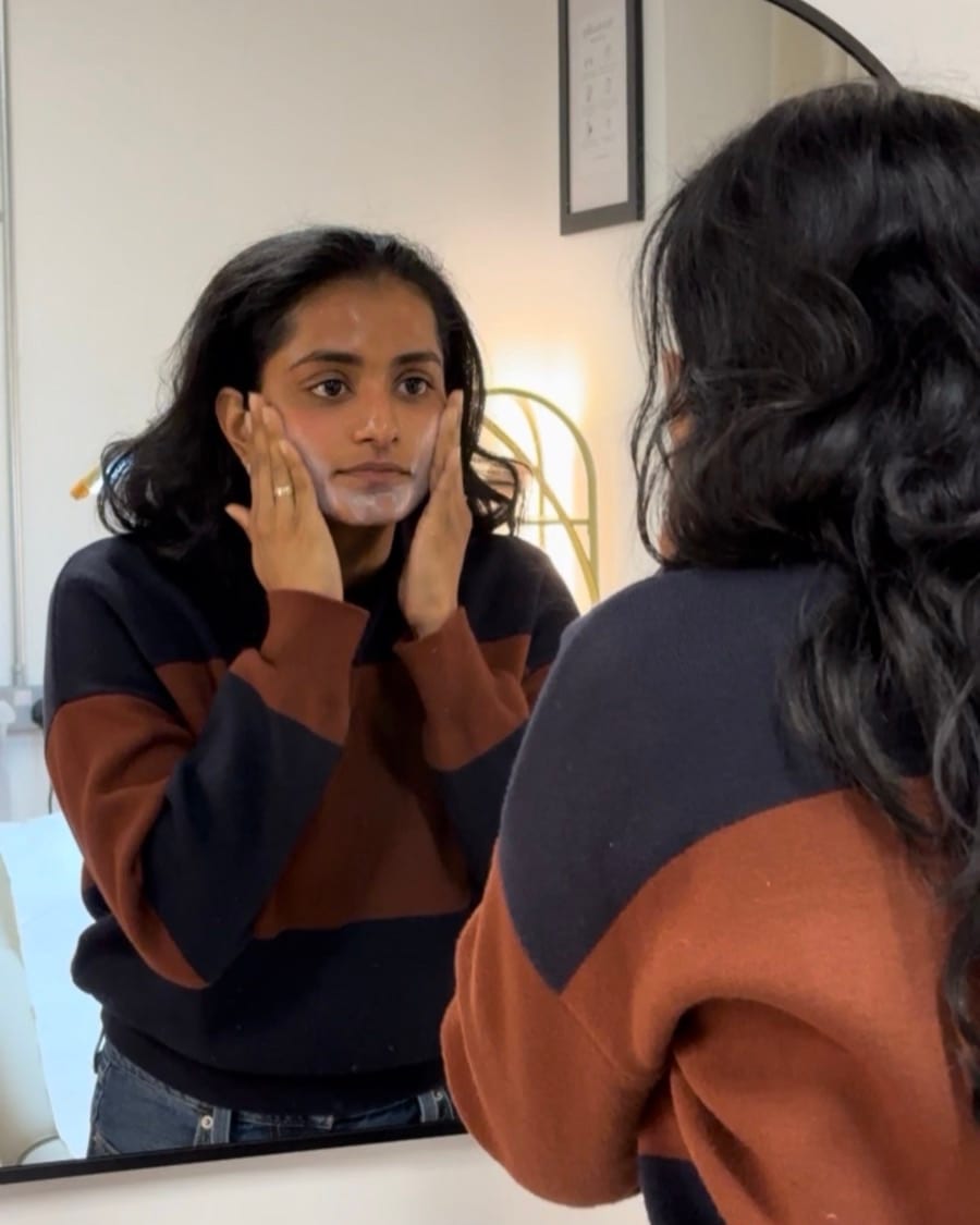 A Skin of Colour client at Melatone Skin Clinic Battersea following an aftercare routine at the mirror